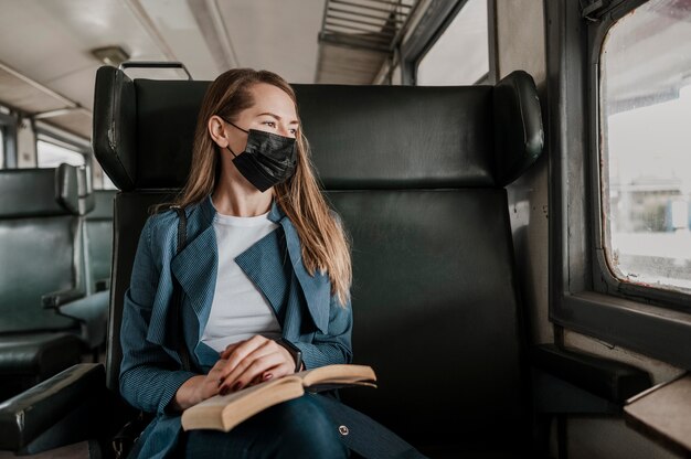 Passeggero in treno che indossa una mascherina medica e guarda fuori dal finestrino