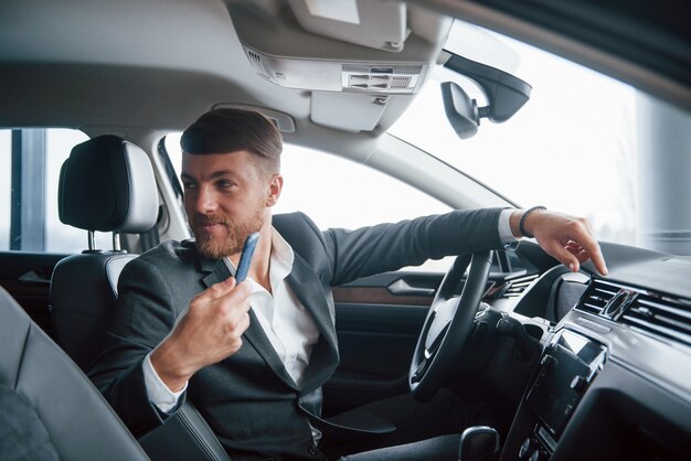 Passeggero sul sedile posteriore. Uomo d'affari moderno che prova la sua nuova automobile nel salone dell'automobile