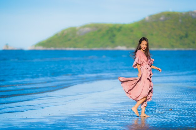 Passeggiata felice di sorriso della bella giovane donna asiatica del ritratto sul mare all&#39;aperto tropicale della spiaggia della natura