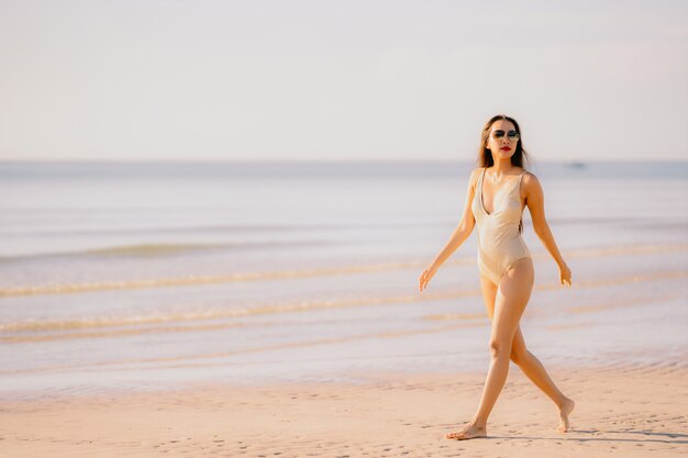 Passeggiata felice di sorriso della bella giovane donna asiatica del ritratto sul mare all&#39;aperto tropicale della spiaggia della natura