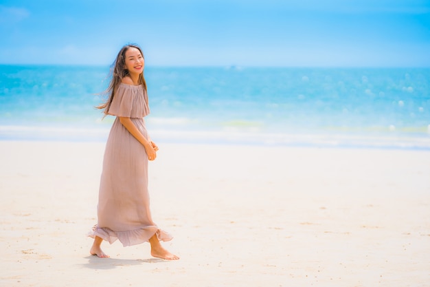 Passeggiata felice di sorriso della bella giovane donna asiatica del ritratto sul mare all&#39;aperto tropicale della spiaggia della natura