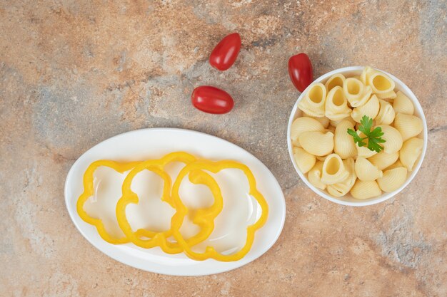 Pasta a forma di conchiglia in una ciotola con pepe e pomodori