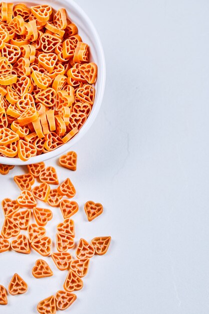 Pasta a forma di del cuore sulla ciotola bianca.