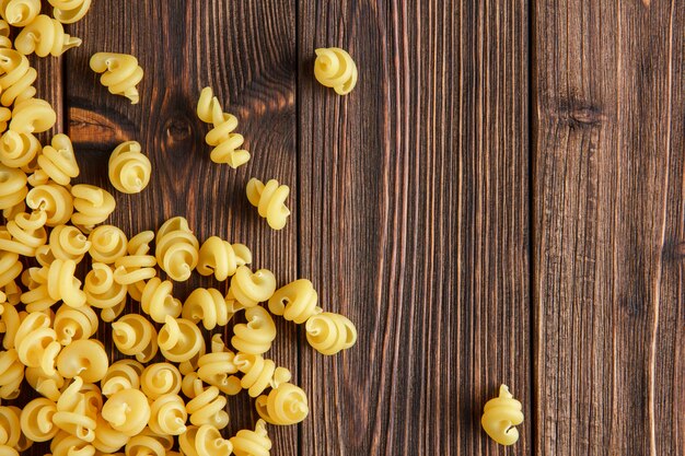 Pasta asciutta sparsa sulla tavola di legno, disposizione piana.