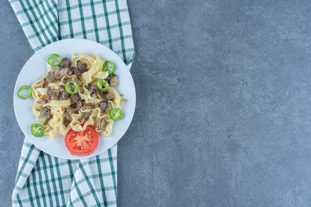 Pasta bollita con pezzi di carne sul piatto bianco.