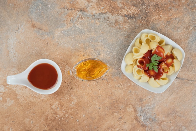 Pasta con prezzemolo e salsa su sfondo arancione con olio