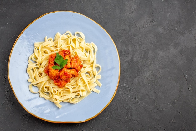 Pasta con vista ravvicinata dall'alto con piatto di carne di pasta appetitosa con carne e sugo sul lato sinistro del tavolo