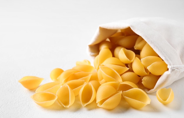 Pasta conchiglie cruda sul primo piano bianco della tavola