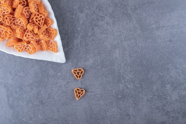 Pasta cruda a forma di cuore su piatto a forma di foglia.