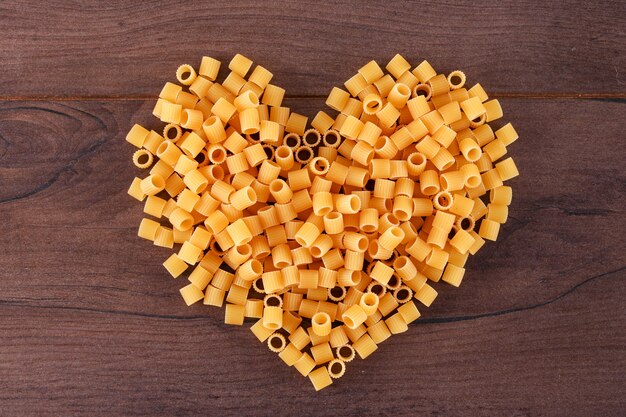 pasta cruda a forma di cuore vista dall'alto sulla superficie in legno