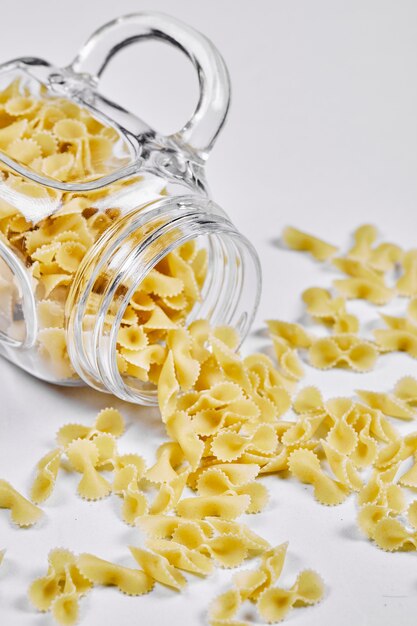 Pasta cruda all'interno del barattolo di vetro sulla superficie bianca