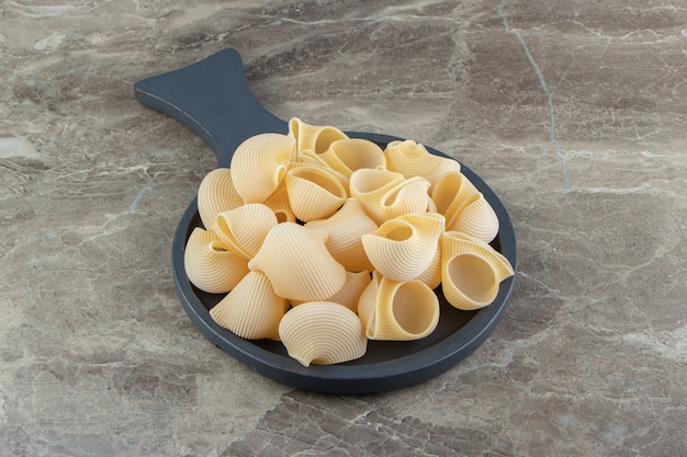 Pasta cruda delle conchiglie sul bordo nero.