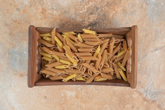 Pasta cruda delle penne nel cestino di legno