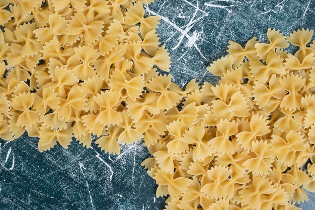 Pasta cruda farfalle formata come nastro su sfondo blu. Foto di alta qualità