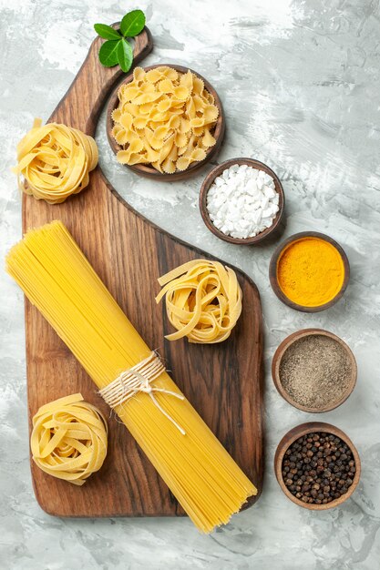 Pasta cruda vista dall'alto con condimenti su sfondo bianco