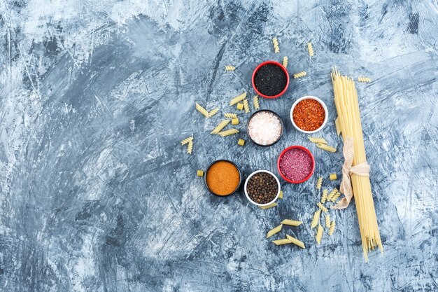 Pasta cruda vista dall'alto con spezie su sfondo grigio intonaco. orizzontale