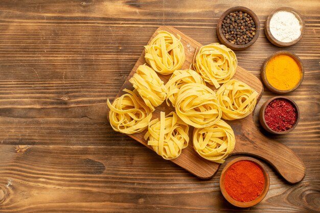 Pasta cruda vista dall'alto progettato pasta con condimenti sulla pasta alimentare pasto pasta sfondo marrone