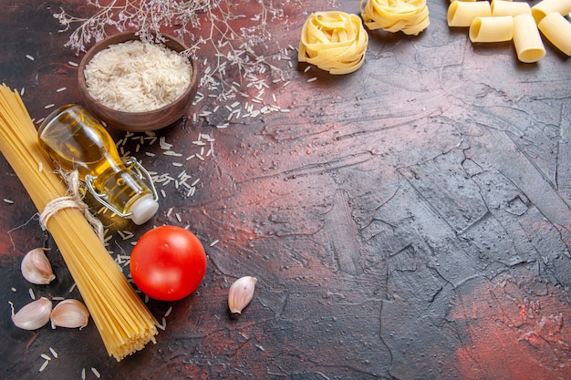 Pasta cruda vista frontale con ingredienti diversi sulla pasta pasta superficie scura cruda