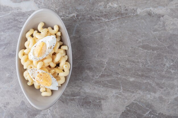 Pasta decorata con uovo sodo in ciotola di ceramica.