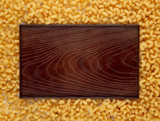 Pasta dei maccheroni del gomito di vista superiore con lo spazio della copia su fondo di legno bianco