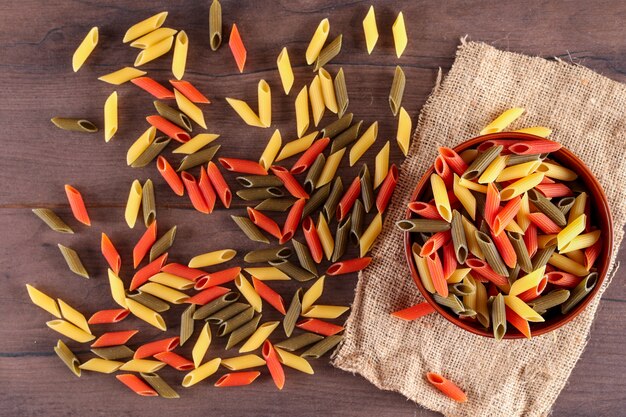 pasta di colore diverso in lamiera vista dall'alto su tela di sacco su superficie di legno