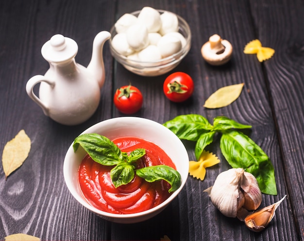 Pasta di farfalle e salsa di pomodoro con ingredienti sul tavolo di legno