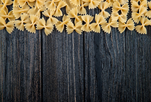 Pasta di farfalle vista dall'alto sulla parte superiore con spazio di copia su fondo di legno nero