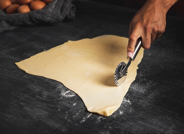 Pasta di taglio dell'uomo del primo piano con la taglierina della pizza