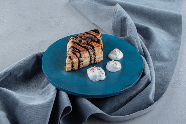 Pasta dolce decorata con cioccolato posta su tavola blu. Foto di alta qualità