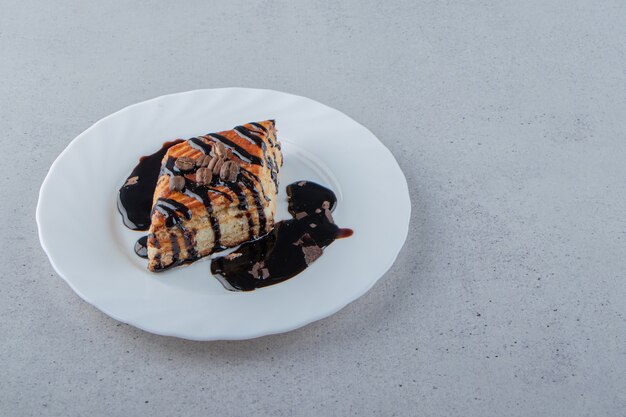 Pasta dolce decorata con sciroppo di cioccolato posto su piatto bianco. Foto di alta qualità