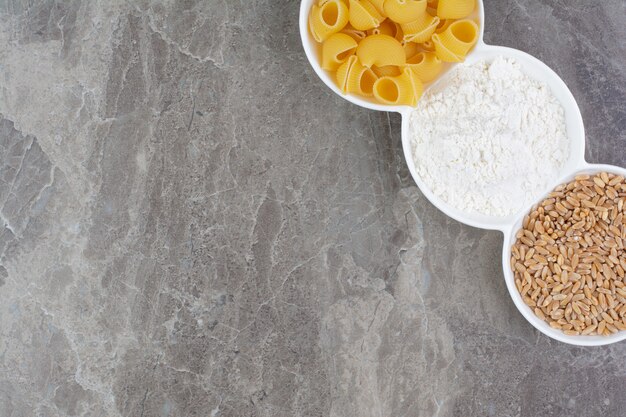 Pasta e ingredienti in coppe di ceramica bianca.