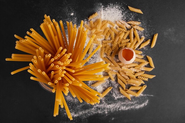 Pasta e uova sulla superficie nera, vista dall'alto.