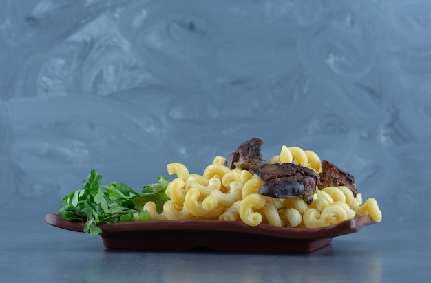 Pasta fatta in casa con carne secca sul piatto marrone.