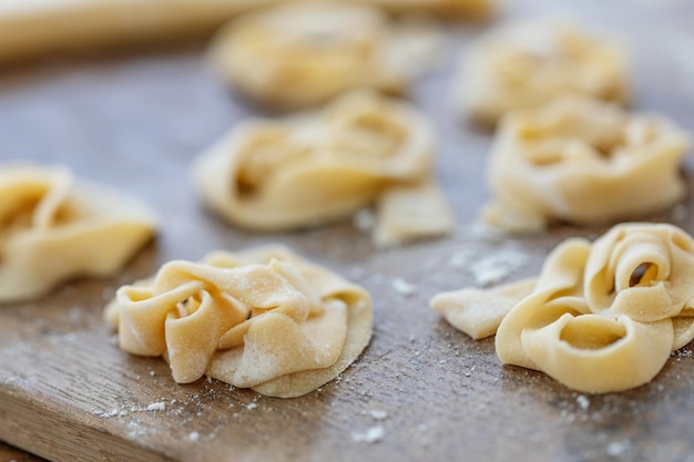 Pasta fresca fatta in casa con farina su tavola di legno sul tavolo.