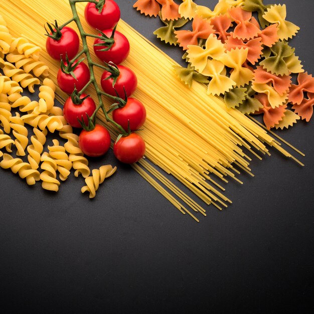 Pasta italiana cruda e pomodorini sopra il piano di lavoro della cucina