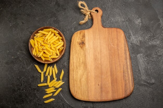 Pasta italiana cruda vista dall'alto all'interno del piatto marrone su grigio