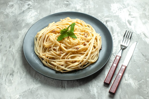 Pasta italiana cucinata vista frontale con posate su sfondo bianco