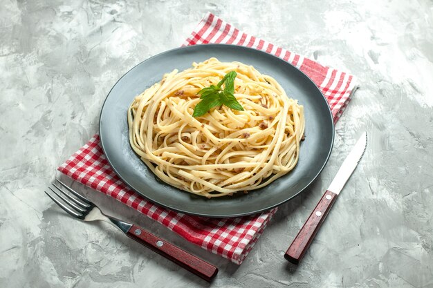 Pasta italiana cucinata vista frontale con posate su sfondo bianco