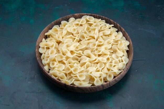 Pasta italiana di mezza vista superiore all'interno del piatto su blu scuro