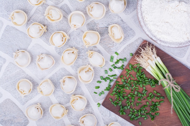 Pasta khinkali caucasica su una tavola di legno con cipolle verdi