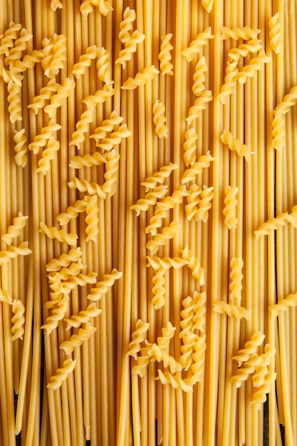 Pasta maccheroni di fusilli vista dall'alto con spaghetti su sfondo. verticale