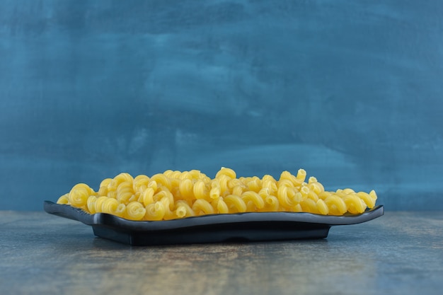 Pasta riccia nel piatto di legno, sullo sfondo di marmo.