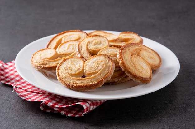 Pasta sfoglia più palmier in piatto su fondo nero dell'ardesia