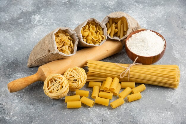 Paste in cestino rustico con mattarello e una tazza di legno di farina intorno.