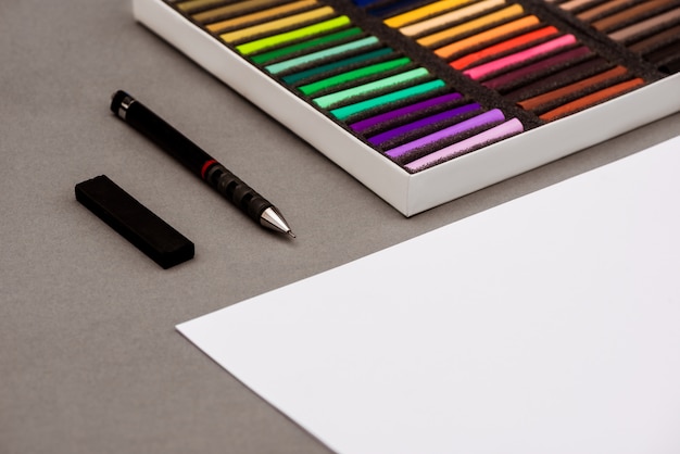 Pastello colorato, penna, carta sul tavolo grigio
