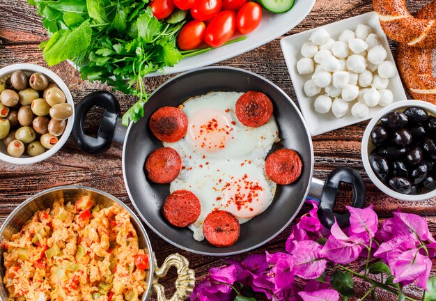 Pasti deliziosi di vista laterale in padella con insalata, sottaceti, fiori su superficie di legno