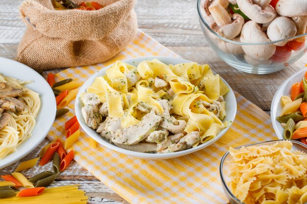 Pasti di pasta assortiti in piatti con pasta cruda e funghi