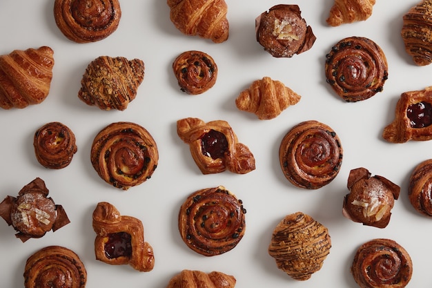 Pasticcini dolci, croissant, turbinii e cupcakes isolati su sfondo bianco, preparati con una ricetta speciale da farina, zucchero, pronti per la vendita in pasticceria. Deliziosa pasticceria. Concetto di cibo spazzatura