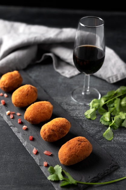 Pasto contenente crocchette al prezzemolo e un bicchiere di vino