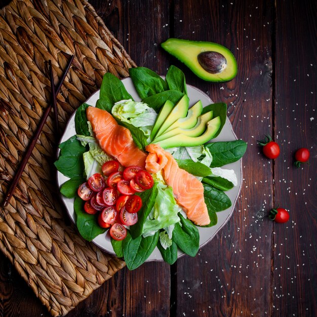 Pasto delizioso di vista superiore in piatto con le bacchette e l'avocado su fondo di legno.